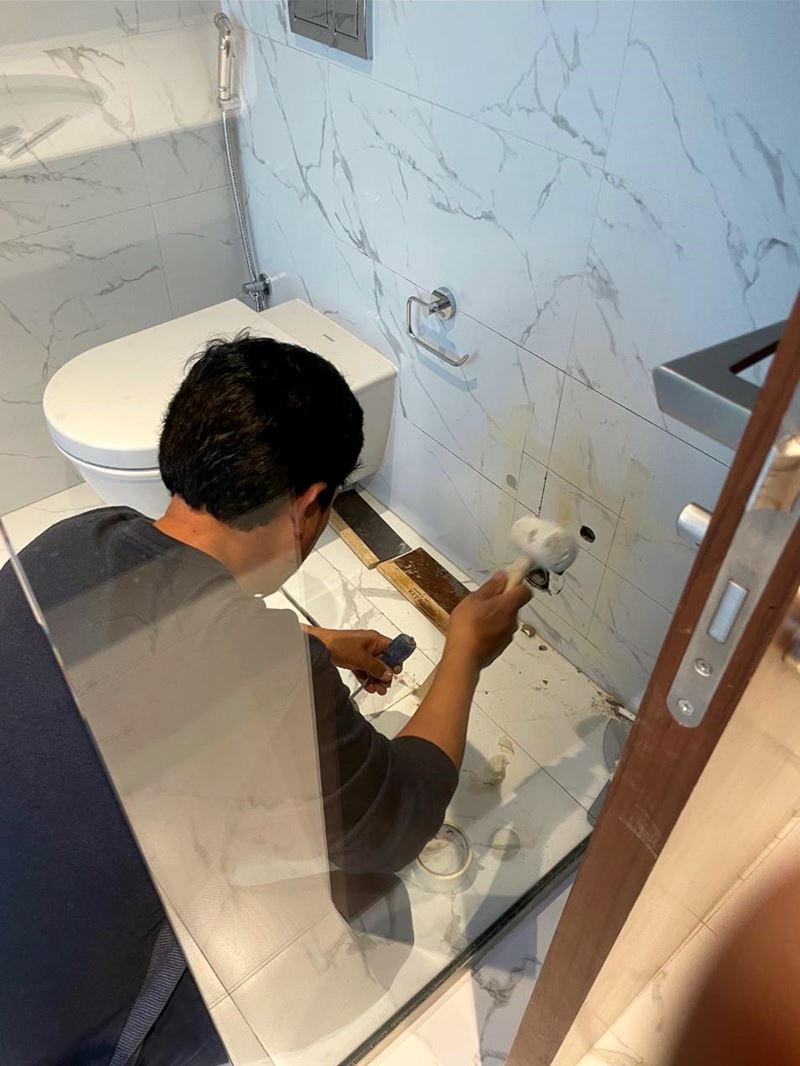 Technician opening bathroom tiles to repair concealed plumbing