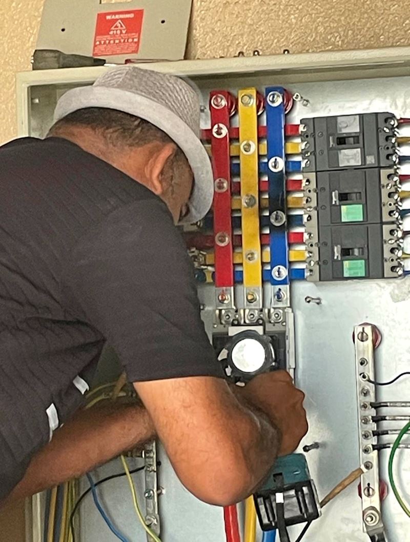 Electrician working on a distribution board with colour-coded busbars