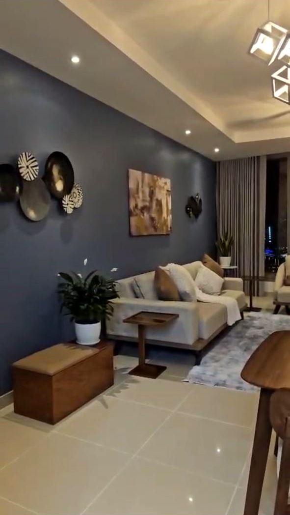 Living room with a deep blue painted feature wall, recessed lights and pendant fittings