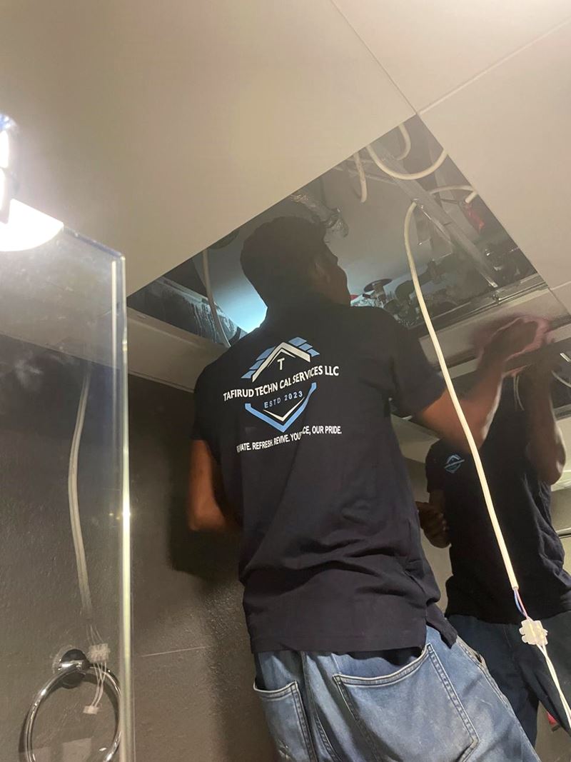 Tafirud technician in company uniform working inside an open ceiling
